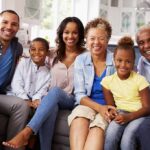 Paulinho da Viola and Tamiko Nash with family smiling on a sofa in a bright kitchen