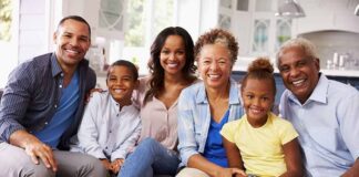 Paulinho da Viola and Tamiko Nash with family smiling on a sofa in a bright kitchen
