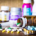Aid Freeze, Clinics Vanish – Infections Loom Medicine pills and syringe on table with brown bottle