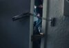 masked intruder peeking through chained door