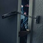 masked intruder peeking through chained door