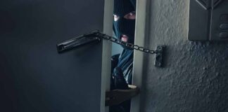 masked intruder peeking through chained door